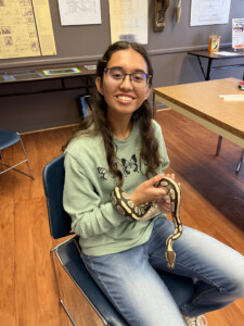 Photo of a teen leader holding a snake during a Teen STEM Cafe on herpetology