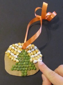 Glueing seeds and beans on the cardboard form in the shape of a Christmas tree.