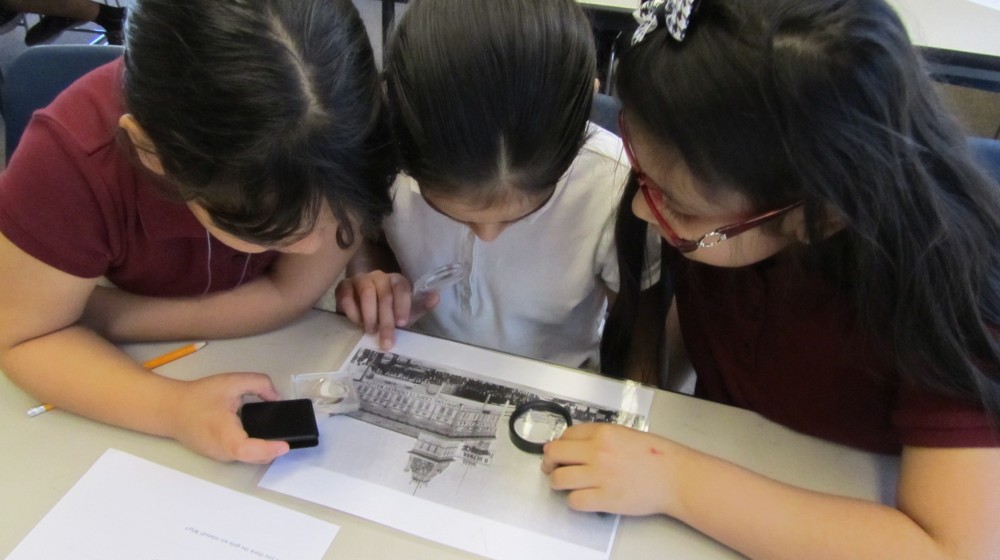 Three children looking over an old photograph of Phoenix during a The Square PHX field trip.