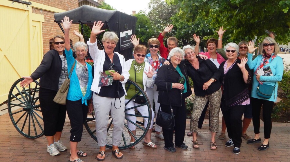 A large group waves at the camera as they enjoy their visit to Rosson House and historic The Square PHX..