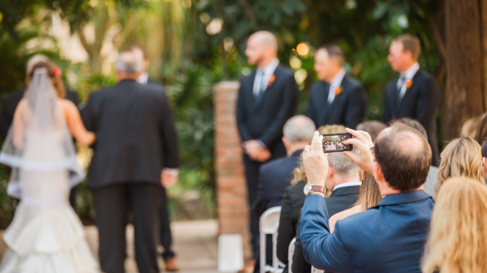 A wedding guest takes a photo of the bride and groom during their wedding at The Square PHX.