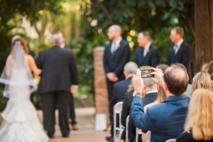 A wedding guest takes a photo of the bride and groom during their wedding at The Square PHX.
