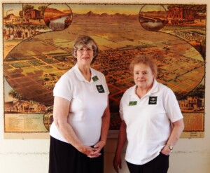 Longtime The Square PHX volunteers Liz and Pat, posing in front of a map of Phoenix from 1895.