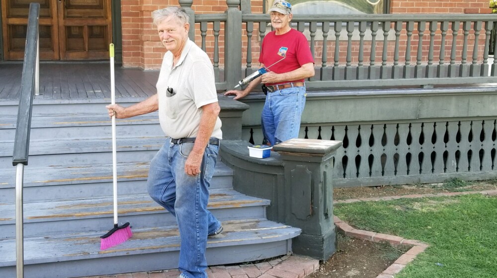 Two The Square PHX volunteers, cleaning and repairing the front steps of Rosson House.