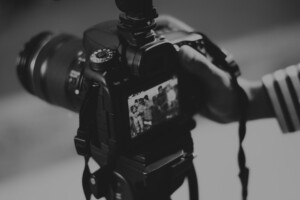 Black and white photograph of a digital camera being used to take a picture of a family.