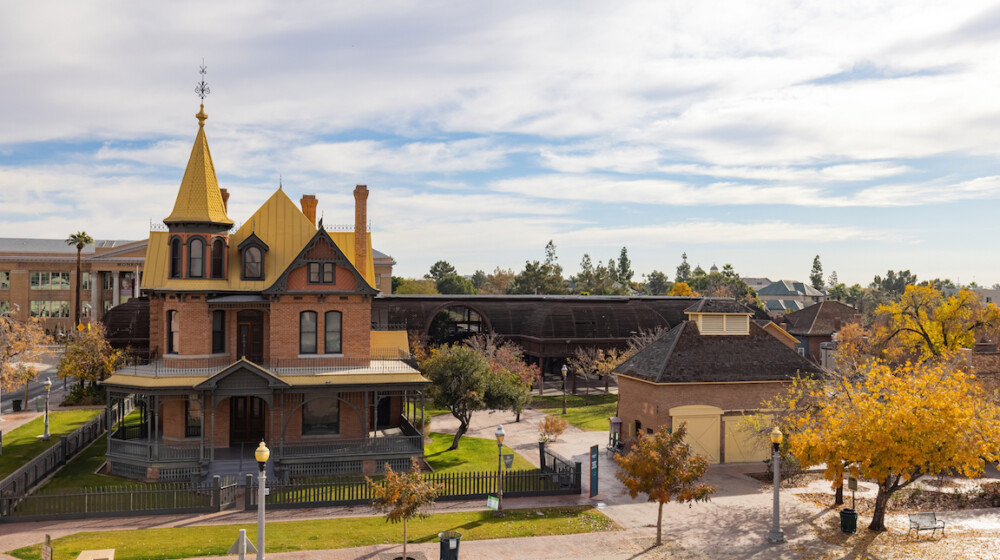 A picture of Rosson House Museum and the Visitor Center Carriage House during winter at The Square PHX, with the leaves on many of the trees turing yellow.