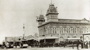 A picture of what is now Downtown Phoenix from approximately 1910. The streets are made of dirt and the Heyman Furniture Co. building is in the background. People, horses, and trolleys are in the foreground.