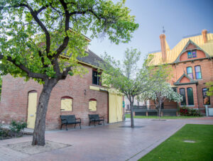 A picture of the Burgess Carriage House and Rosson House at historic The Square PHX, with green grass and trees with bright, new leaves.