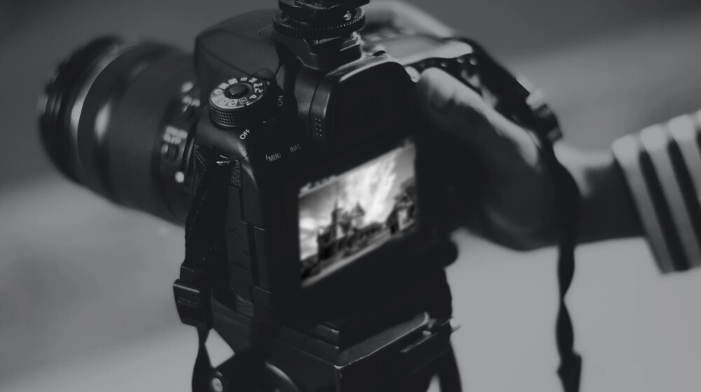 A black and white picture of someone taking a picture with an advanced camera.