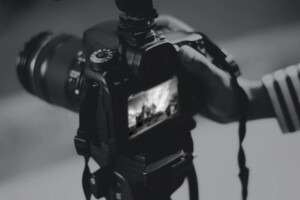 A black and white picture of someone taking a picture with an advanced camera.