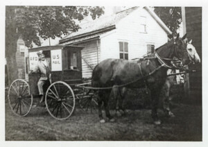 A photo of a horse-drawn mail delivery cart with a mailman.