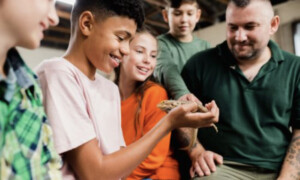 A picture of students learning about a lizard.