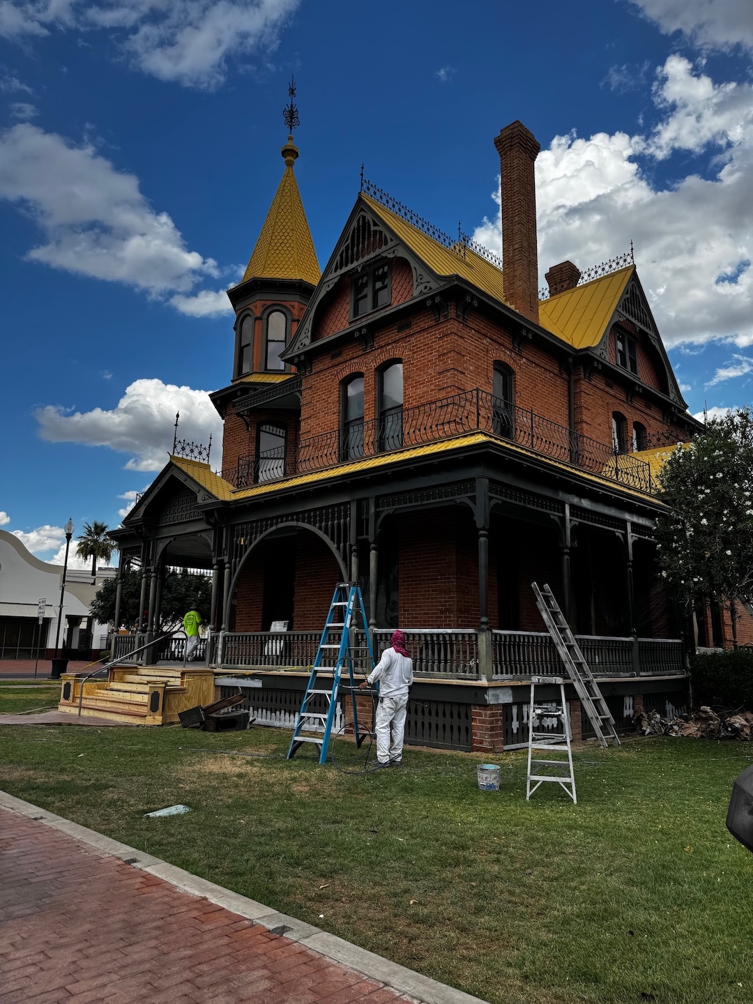 A brick Victorian Era house with construction work being done on the wide front porch.