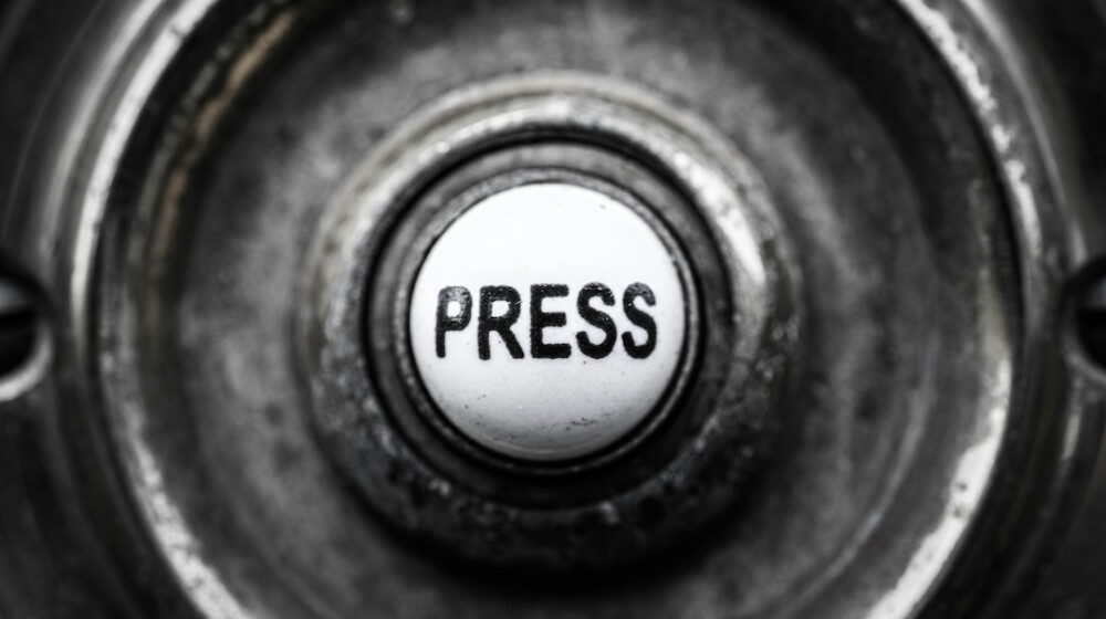 A black and white photo of an antique doorbell with a button labeled, 